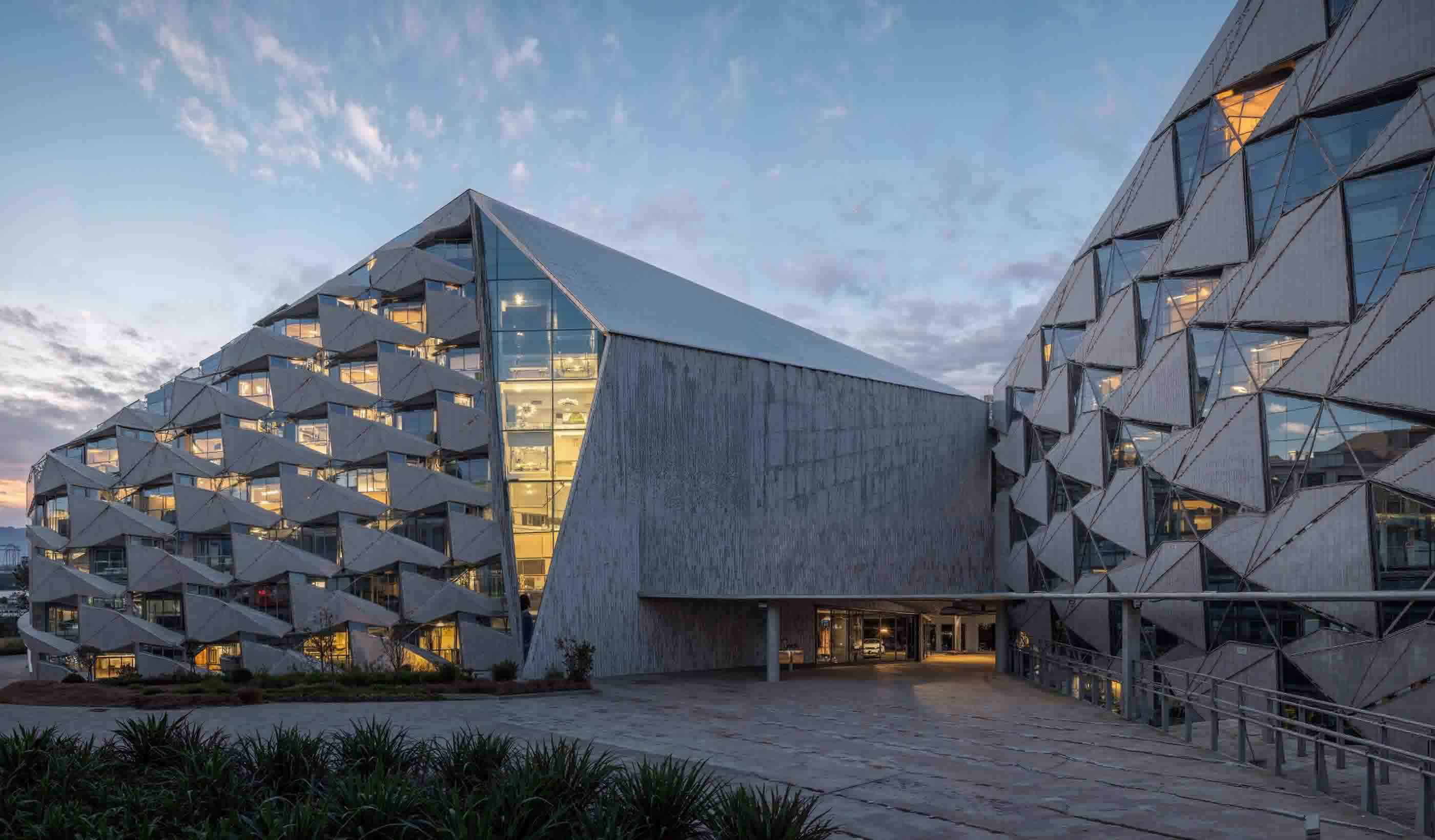 An AI-assisted architectural building with a faceted glass facade photographed at dusk.